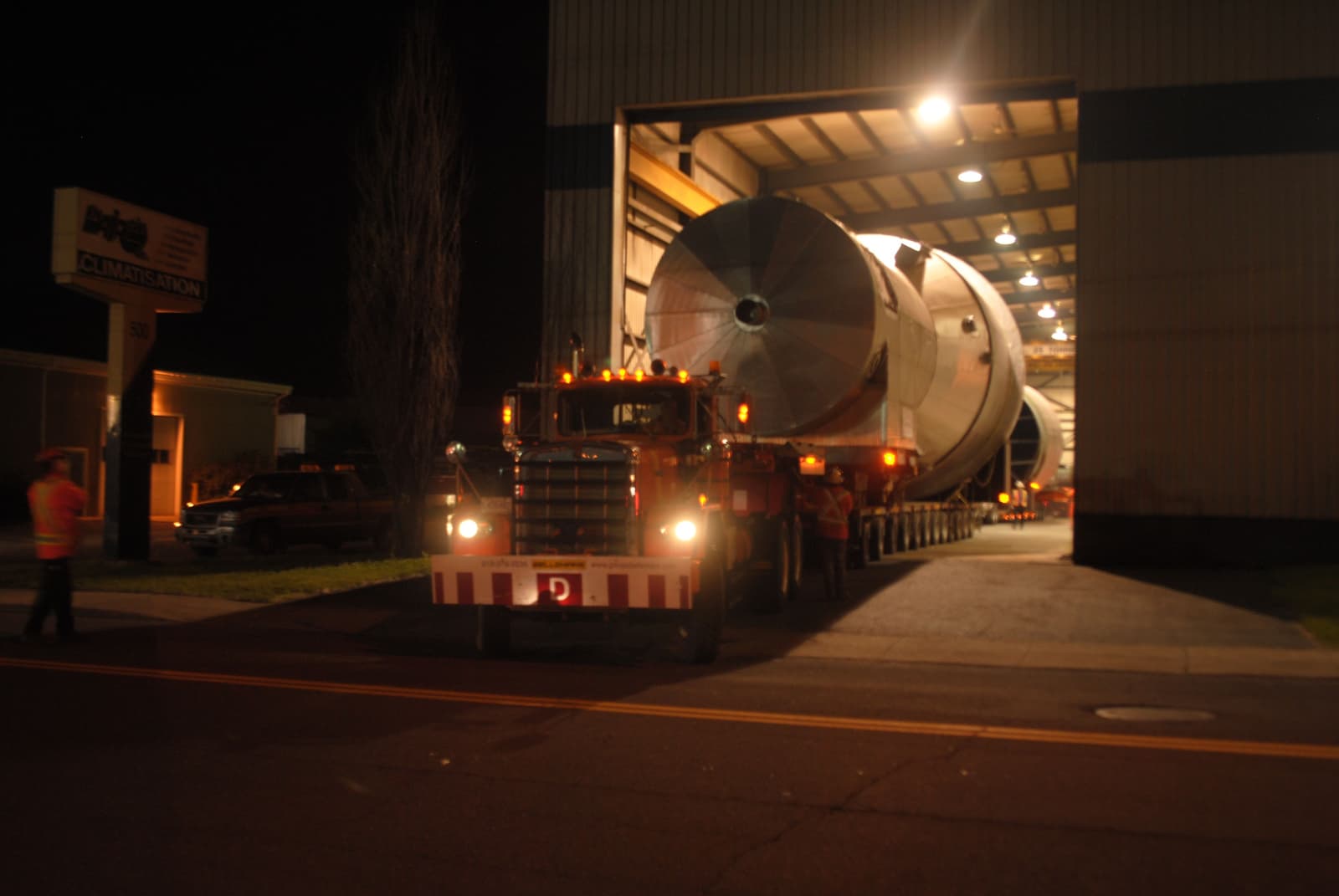 camion sortant d'une usine avec une immense composante en acier
