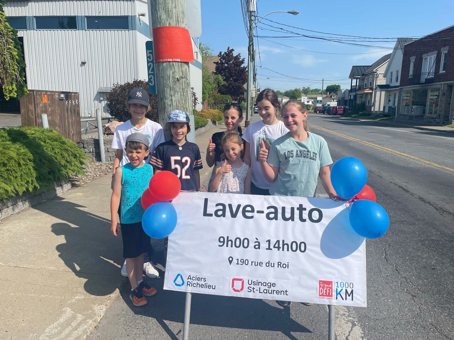 Plusieurs enfants devant une pancarte pour annoncer le lave-auto