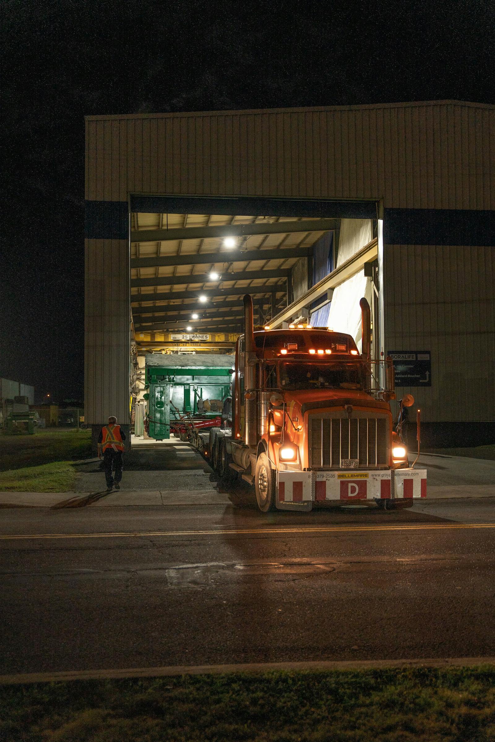 camion de transport orange qui quitte l'usine